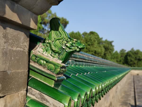 A perspective picture of wall with green tiles in the Temple of Heaven. The front most tile is dragon-shaped.